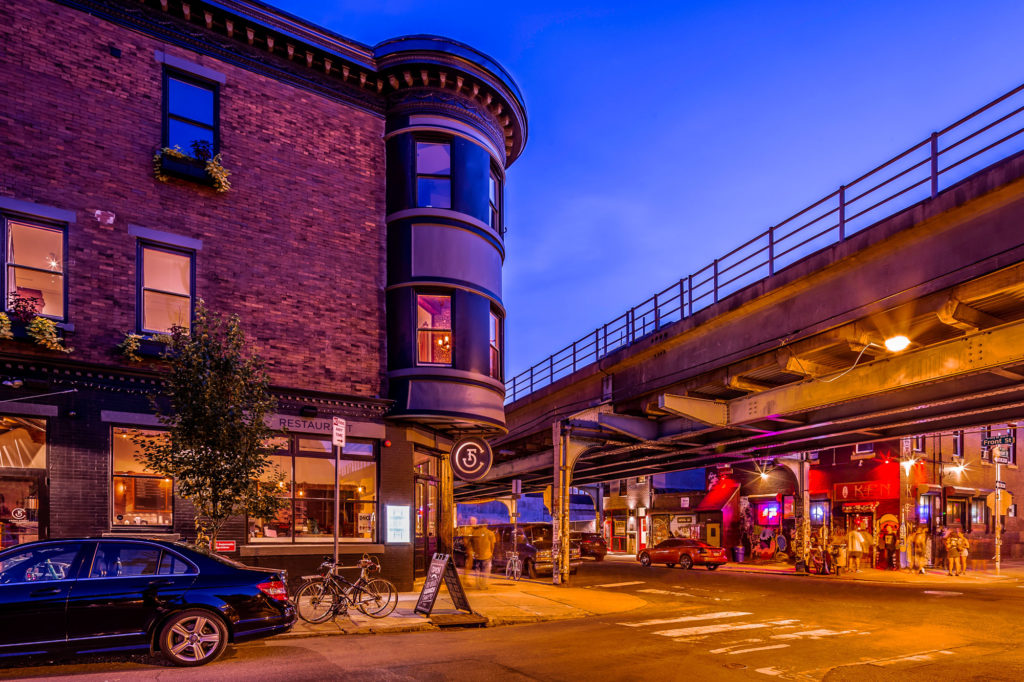 Street corner next to elevated subway line.